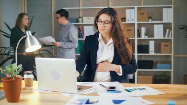 Una donna d'affari incinta di successo lavora con i colleghi in un comodo ufficio moderno