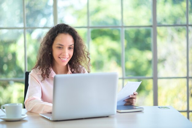 Una donna d'affari latina sorridente e fiduciosa che lavora in ufficio.