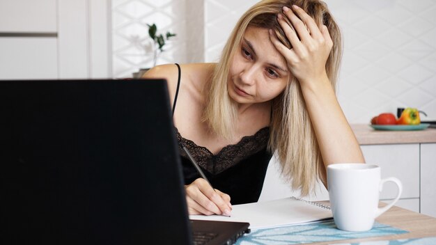 Una donna d'affari lavora a casa o istruisce uno studente usando il suo laptop