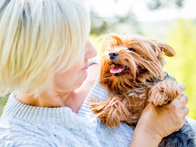 Una donna dai capelli chiari sta giocando con un giovane cane di razza Yorkshire Terrier