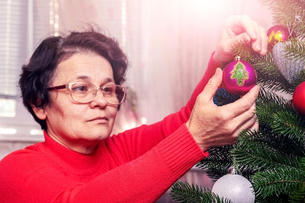 Una donna decora un albero di Natale e Capodanno Preparazione per Natale e Capodanno