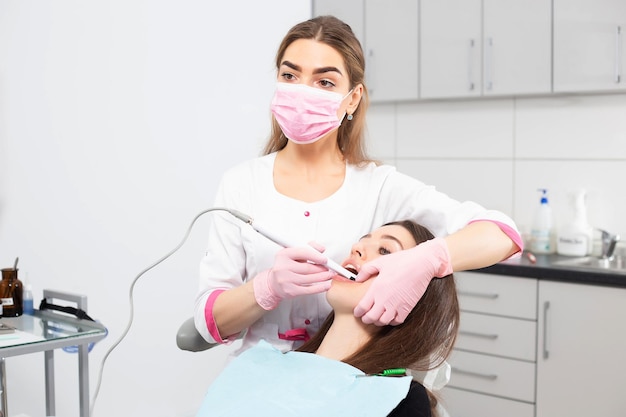 Una donna dentista fotografa i denti di un paziente utilizzando una fotocamera speciale in una moderna poltrona odontoiatrica