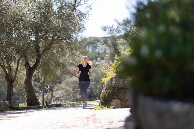 Una donna di forma fisica adulta che fa jogging nel parco verde