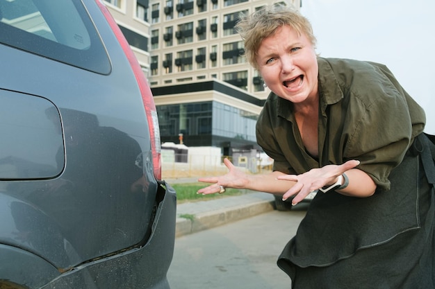 Una donna di mezza età con un taglio di capelli corto è scioccata dai danni al paraurti della sua auto