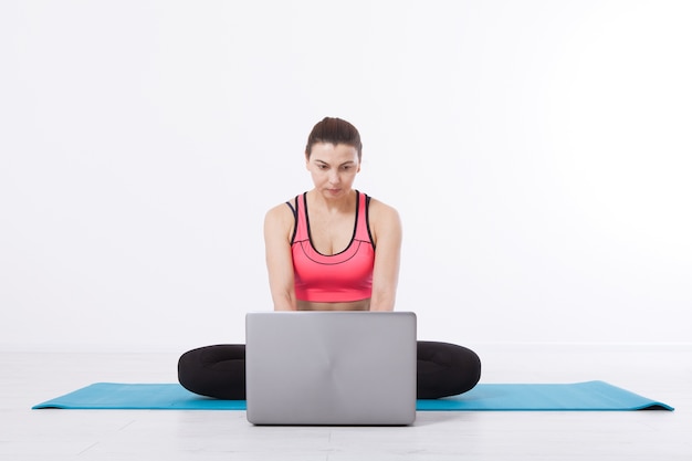 Una donna di mezza età conduce corsi di yoga utilizzando un laptop e la comunicazione Internet