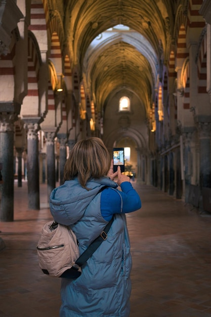 Una donna di mezza età scatta una foto con il cellulare all'interno di una cattedrale