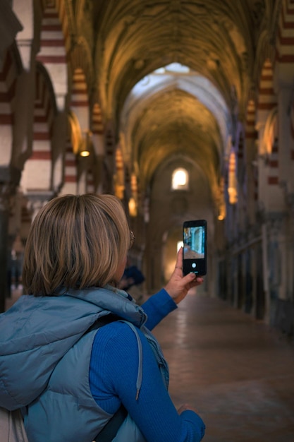 Una donna di mezza età scatta una foto con il cellulare all'interno di una cattedrale