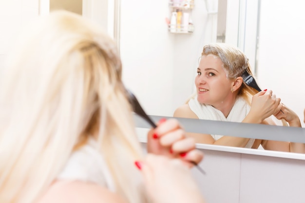 Una donna di mezza età si tinge i capelli a casa, in casa