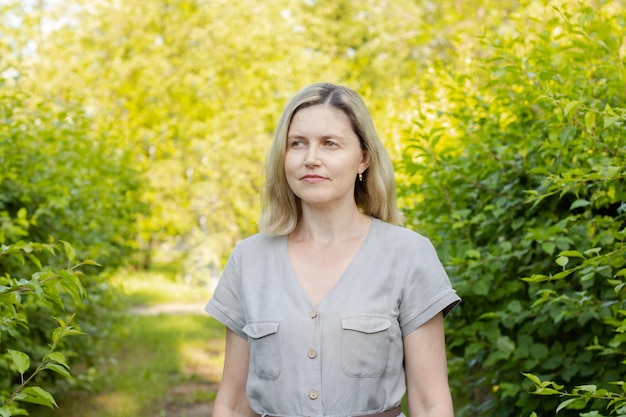 Una donna di mezza età si trova nel parco Donna matura con i capelli biondi