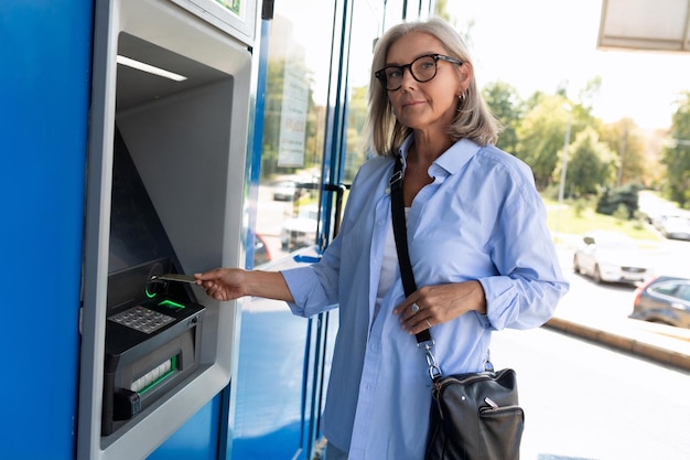 Una donna di mezza età vuole prelevare denaro da un bancomat