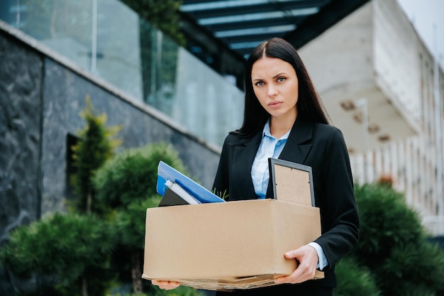 Una donna disoccupata che porta una scatola che raffigura la perdita del lavoro e la disoccupazione donna senza lavoro e sola