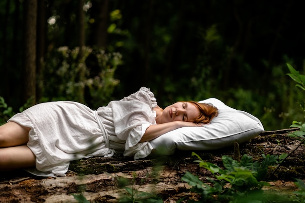 Una donna dorme nel bosco su un cuscino