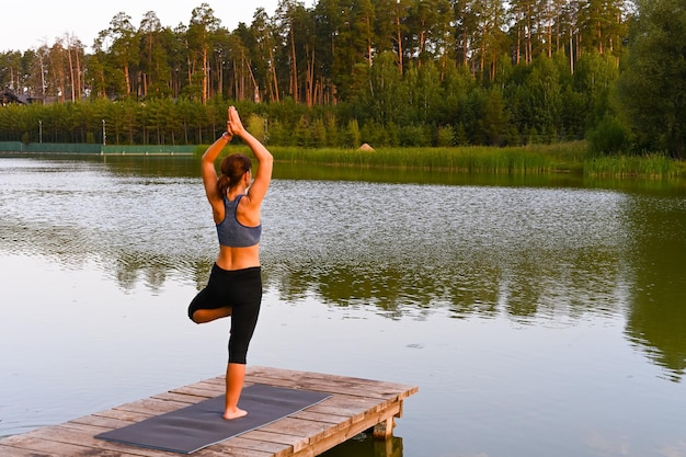 Una donna è impegnata in esercizi di fisioterapia sul lago in natura. Il concetto di trattamento delle malattie.