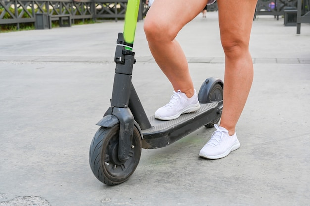 Una donna è in piedi con uno scooter sull'argine di Kazan. Trasporto ecologico.