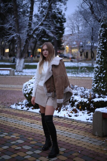 una donna è in piedi nella neve fuori con un cappotto su