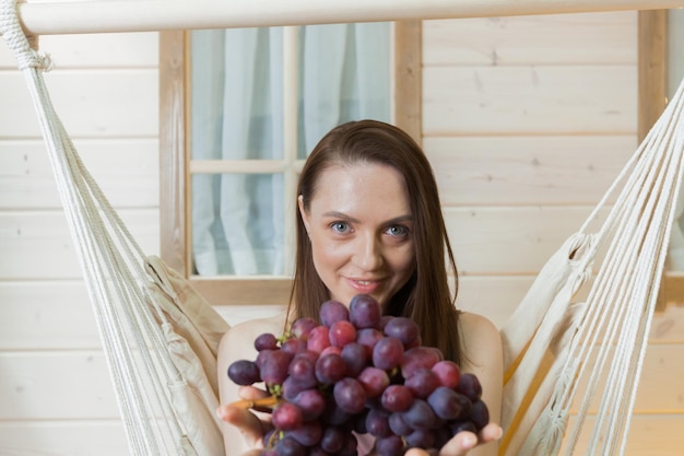 Una donna è seduta su un'amaca sorridente con la frutta in mano.