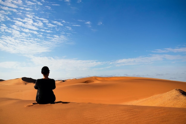 Una donna è seduta sulla duna di sabbia dorata del deserto del Namib. Africa