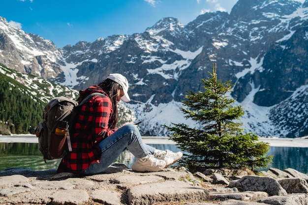 Una donna è seduta sulla riva di un lago Morskie Oko Tatra