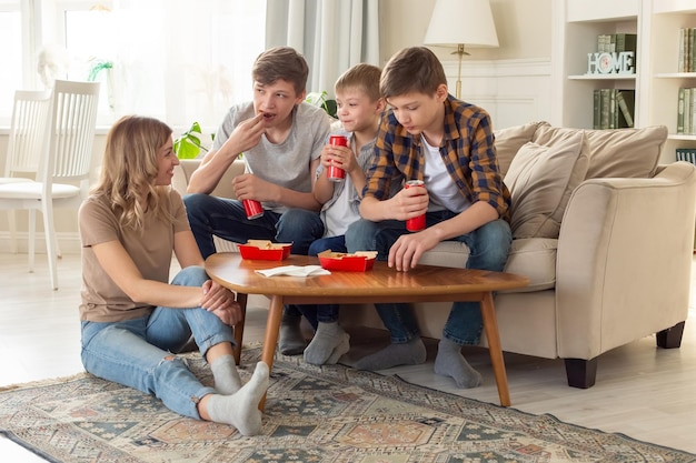 Una donna e tre adolescenti mangiano fast food in scatole rosse e bevono bevande in lattine rosse