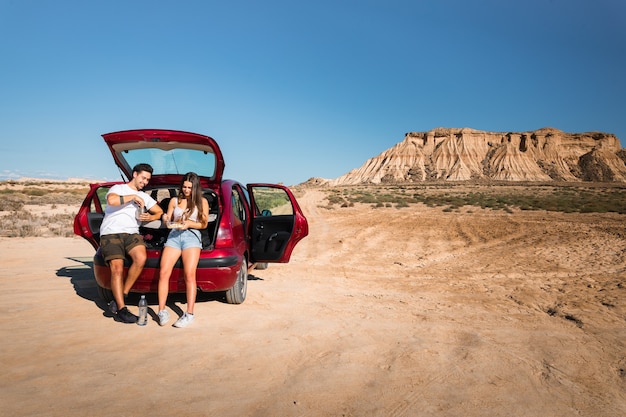 Una donna e un uomo che mangiano e chiacchierano in auto durante il viaggio nel deserto di Bardenas Reales, Navarra, Paesi Baschi.