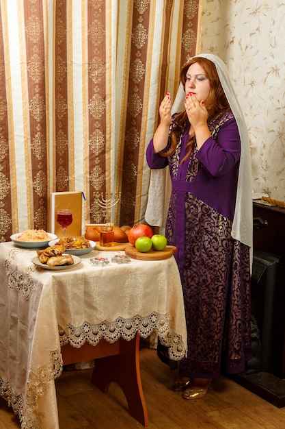 Una donna ebrea con un velo che le cade dai capelli prega alla tavola festiva di Rosh Hashanah