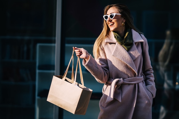 Una donna elegante in un cappotto e occhiali da sole per lo shopping