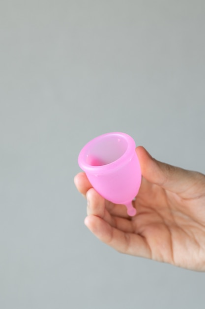 Una donna europea tiene in mano una coppetta mestruale rosa in silicone per l'igiene e la cura delle donne