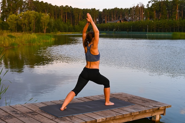 Una donna fa sport sul lago. Il concetto di attività fisica in natura.