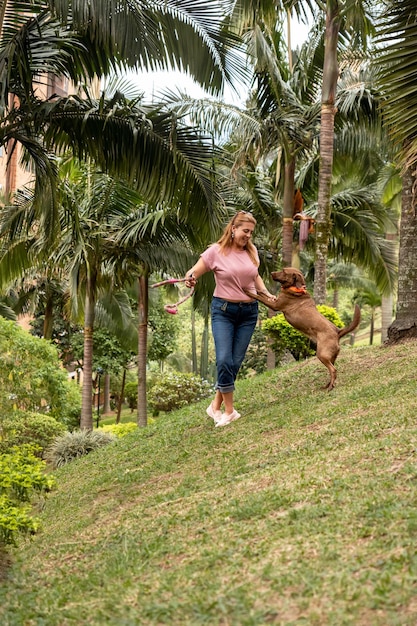 Una donna felice che gioca con il suo cane in un luogo tropicale