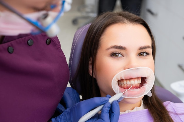 Una donna felice che si fa controllare i denti in un ufficio dentistico.