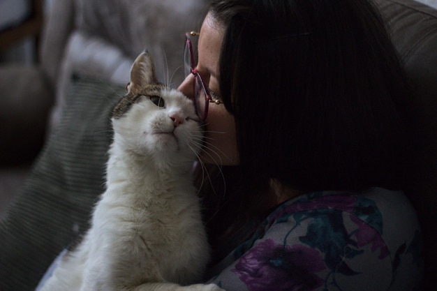 Una donna felice con gli occhiali insieme al suo gatto amorevole