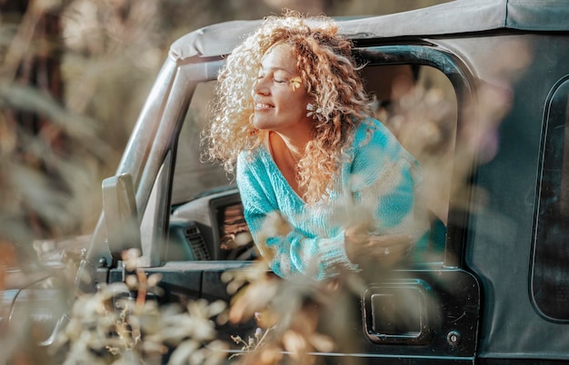 Una donna felice e libera si gode il sole e viaggia con l'auto sorridendo ad occhi chiusi nei boschi della foresta destinazione del veicolo avventura Persone e attività ricreative all'aperto Avventura stile di vita signora libertà