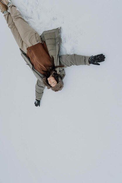 Una donna felice nella foresta invernale che si gode la prima neve Una giovane donna con un cappello si diverte nella natura invernale