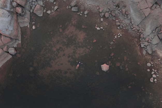 Una donna giace sulla superficie dell'acqua nella laguna Vista dall'alto Costa di granito