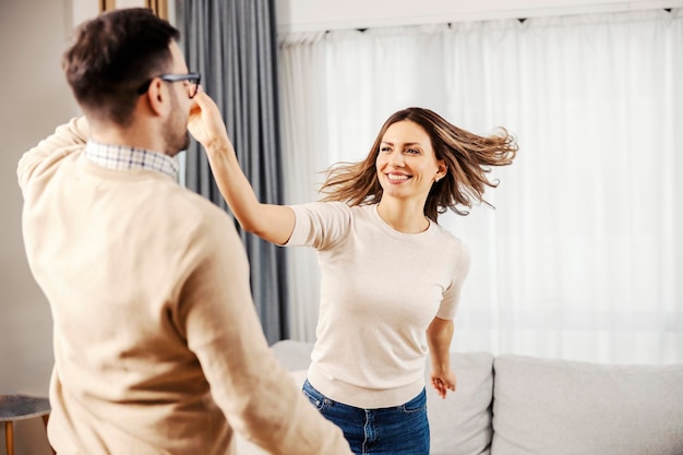 Una donna gioiosa che balla con suo marito nel loro nuovo appartamento