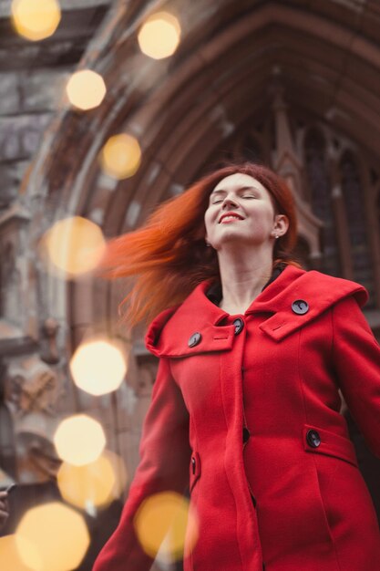 Una donna gioiosa in cappotto rosso in un ritratto di strada