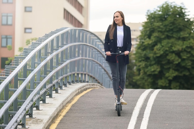 Una donna guida uno scooter elettrico in città Trasporto urbano popolare