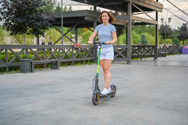 Una donna guida uno scooter sull'argine di Kazan Trasporto ecologico