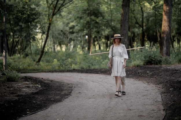 Una donna in abito bianco cammina su un sentiero nel bosco