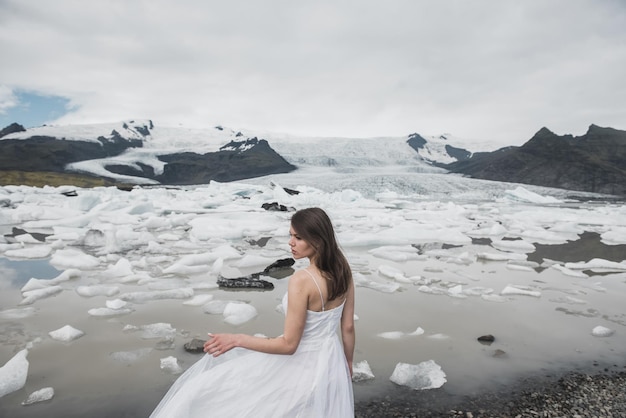 Una donna in abito bianco si staglia sullo sfondo dei ghiacciai in Islanda