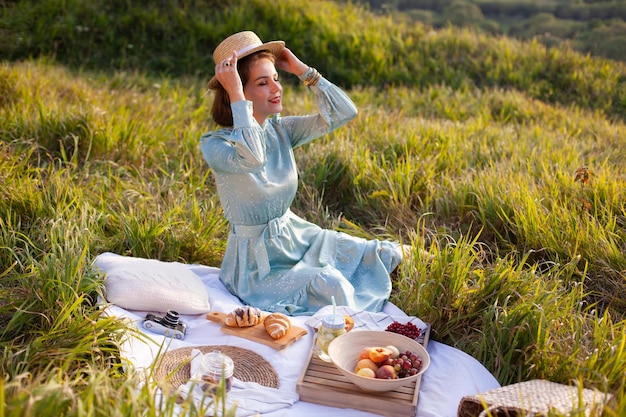 Una donna in abito blu si siede su un picnic in un parco con vista panoramica