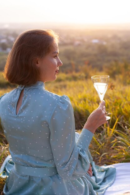 Una donna in abito blu si siede su un picnic in un parco con vista panoramica