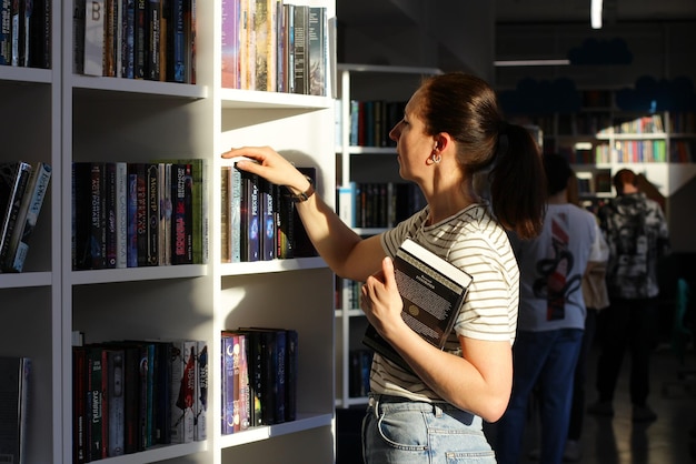 Una donna in biblioteca alla ricerca di un libro il concetto di educazione visita la sala di lettura