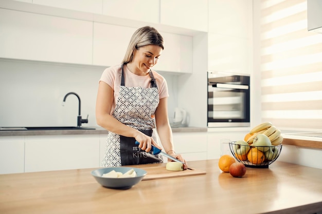 Una donna in buona salute che prepara macedonia di frutta a casa