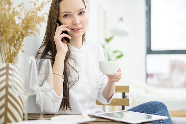 Una donna in camicia bianca sta bevendo un caffè in un bar Un'impiegata in pausa pranzo risolve un problema aziendale per telefono Manager di medio livello