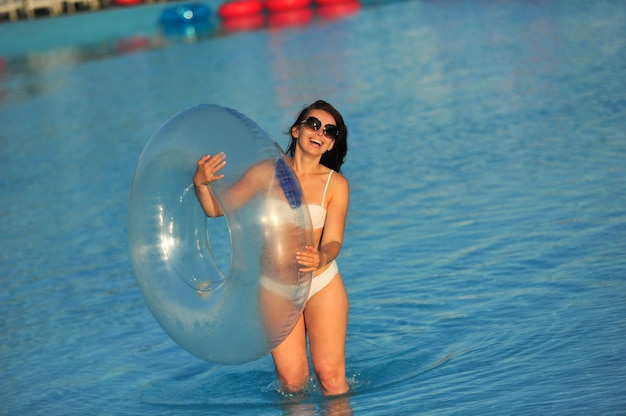 Una donna in costume da bagno bianco con un cerchio gonfiabile in un parco acquatico.