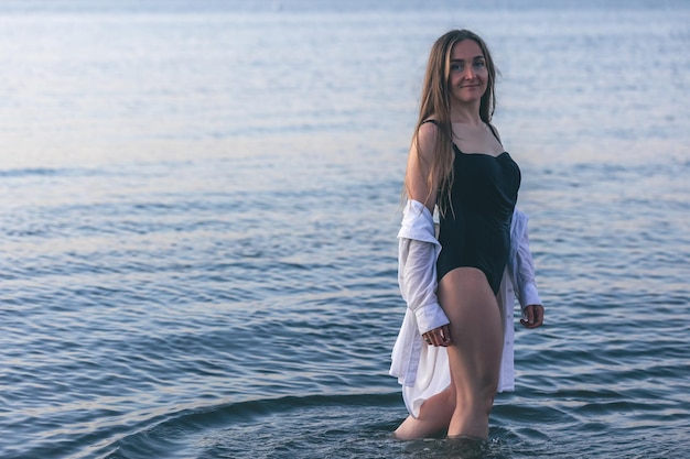 Una donna in costume da bagno e una camicia bianca in mare