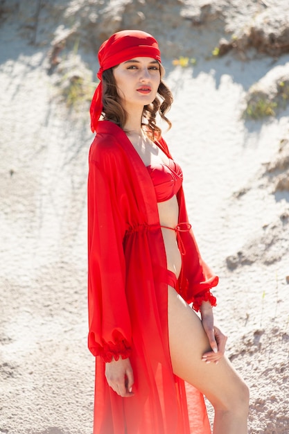 Una donna in costume rosso si trova nella sabbia