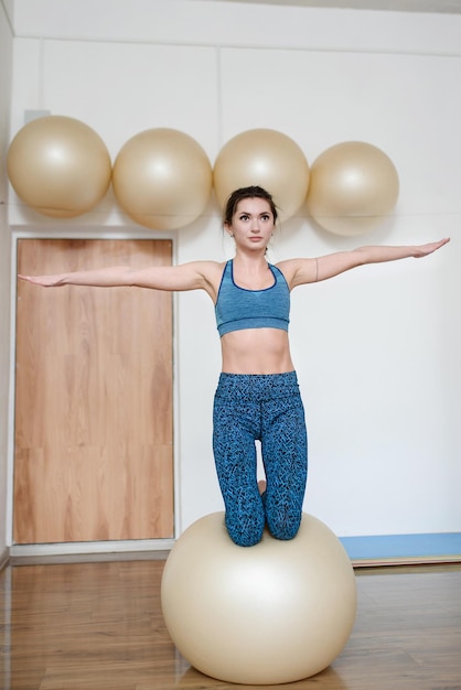 Una donna in forma in palestra si bilancia su un fitballIl concetto di stile di vita sano