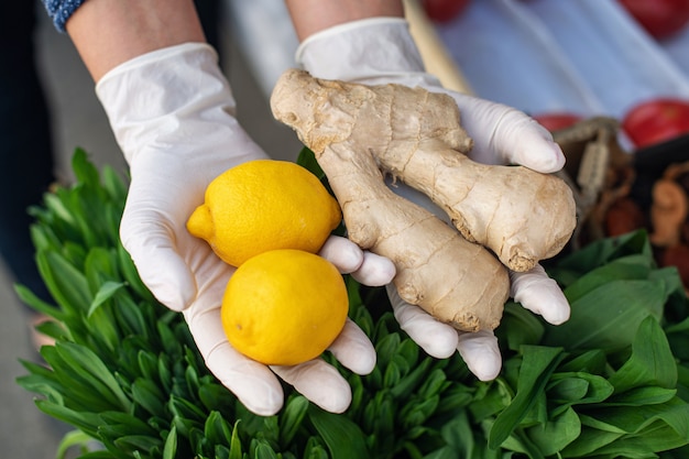 Una donna in guanti usa e getta compra limone e zenzero